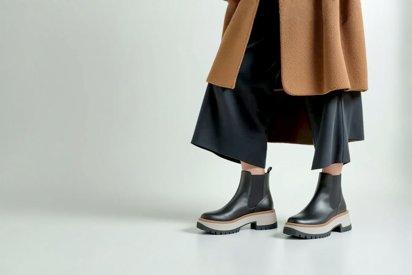 Professional fashion photography style image. A person with a balanced outfit featuring chunky platform ankle boots is shown from the knees down. The focus is on the boots and how they integrate seamlessly with the pants or skirt hem, illustrating good proportion. The background is clean and minimalist to keep the focus on the footwear and styling.