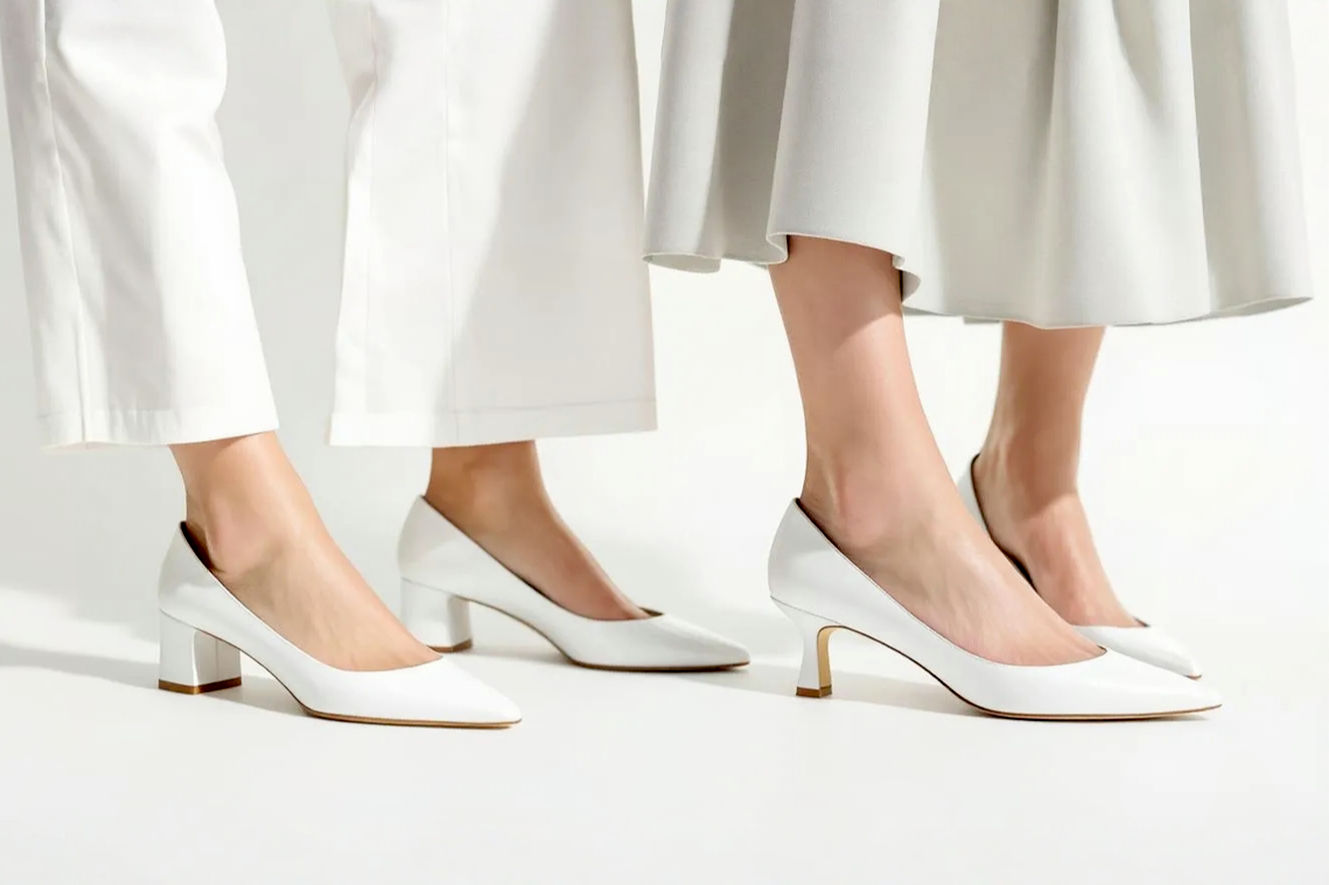 A professional, lifelike photograph showcasing two distinct white low-heeled shoes side-by-side on a minimalist, light background. On the left, a white block low heel (with a sturdy, square heel) paired with a modern, tailored outfit (e.g., wide-leg trousers or a structured midi dress). On the right, a white kitten heel (with a slender, curved heel) paired with a classic, elegant outfit (e.g., a delicate cocktail dress or a pencil skirt). The lighting should be soft and natural, highlighting the textures and shapes of the shoes and outfits, creating a clean, sophisticated, and aspirational feel. Focus on the shoes and lower legs for visual impact. Professional studio photography style.